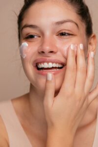 Smiling woman applying moisturizer after Skin Care Chevy Chase facial treatment for glowing skin.